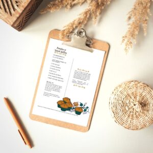 A table with dried flowers and a pen and clipboard, with a recipe for pumpkin muffins